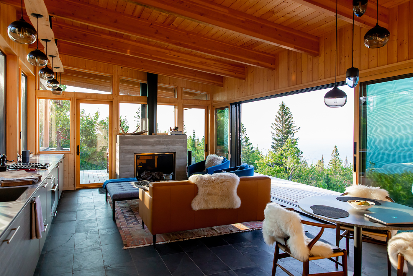 Timber-framed great room opening to an evergreen hillside