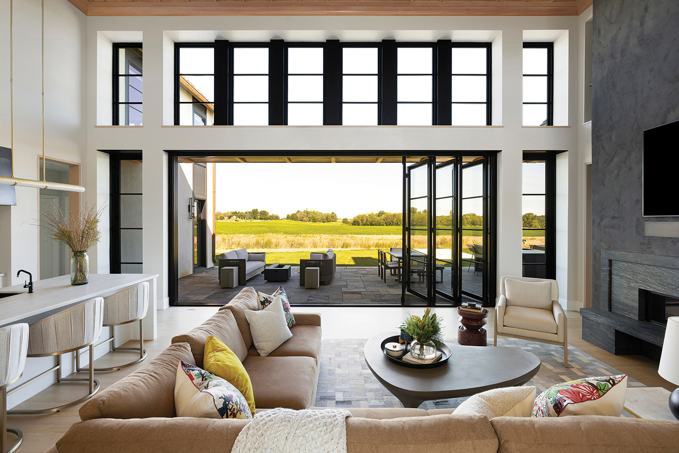 Great room with black-framed windows opening onto open country
